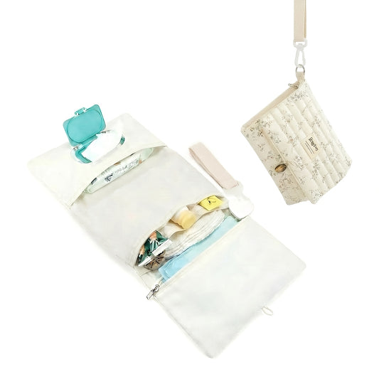 Portable foldable diaper changing clutch unfolded as a padded mat with wipes pocket and folded as a quilted floral crossbody clutch